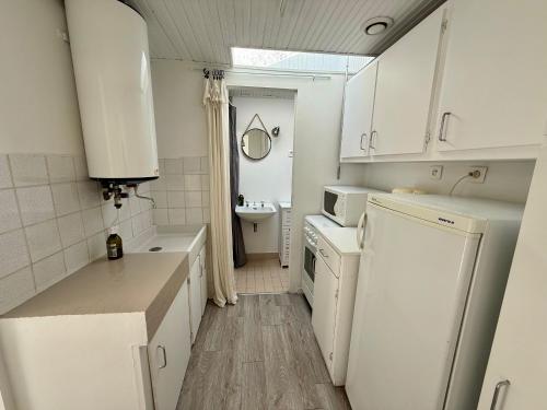 une petite cuisine avec des armoires blanches et un évier dans l'établissement Maison charmante proche plage et commerces avec WIFI - FR-1-652-60, à Saint-Jean-de-Monts