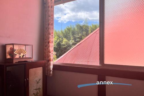 a window with a view of a red roof at もりのもむ Morinomomu Guest House in Mitsuo in Yasuda