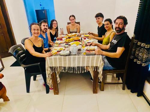 a group of people sitting around a table eating food at Priyavimana resort in Habarana