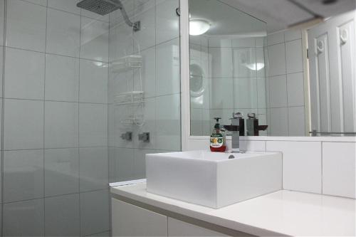 une salle de bain blanche avec un lavabo et un miroir dans l'établissement Seven Seas Unit 5 Caloundra QLD, à Caloundra