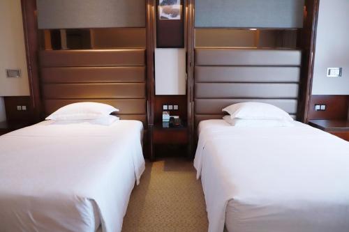 two beds in a hotel room with white sheets at Sheraton Hefei Xinzhan Hotel in Hefei