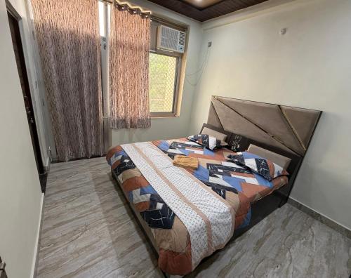a bedroom with a bed with a comforter and a window at Luxury Appartment Radha Kunj in Vrindāvan
