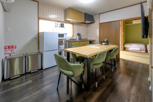 a kitchen with a wooden table and green chairs at COCOSTAY尾道本通り - 千光寺も花火も雨の日も全部にやさしい尾道の宿 - In the middle of the shopping street in Onomichi