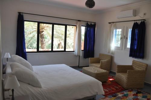 a bedroom with a large bed and two chairs at Maison La Berberina in Goulmima