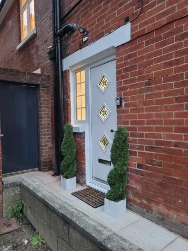 a white door on a brick building with two bushes at Boardlands House 3 Bed home in Southampton