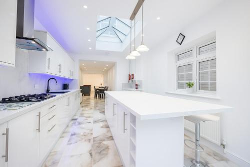 a kitchen with white cabinets and a blue ceiling at Boardlands House 3 Bed home in Southampton