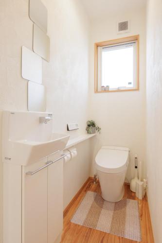 a bathroom with a toilet and a sink and a window at Nicostay Katsuura Beach in Fukuoka