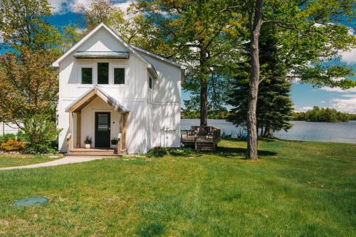 a white house on a lawn with a tree at Serenity Shores 5BD Hot Tub Fishing Hiking in Traverse City