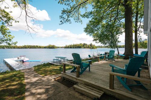 a dock with chairs and a boat on a lake at Serenity Shores 5BD Hot Tub Fishing Hiking in Traverse City