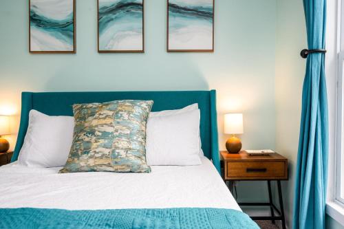 a bed with a blue headboard with a pillow on it at Serenity Shores 5BD Hot Tub Fishing Hiking in Traverse City