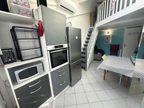 une cuisine avec des appareils en acier inoxydable et un escalier dans l'établissement Pavillon 5 pers avec piscine, parking et jardin à Valras-Plage - FR-1-781-74, à Valras-Plage