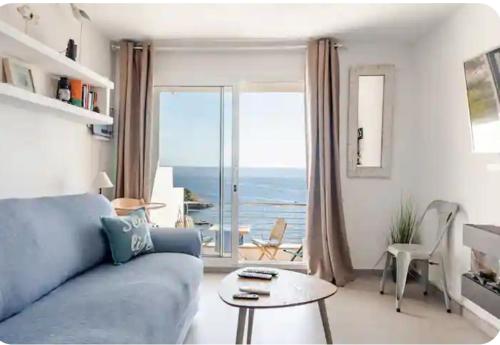 a living room with a blue couch and a large window at "Belvédère de la Mer" Résidence "Icaros" Wifi-Piscine-Pkg in Begur