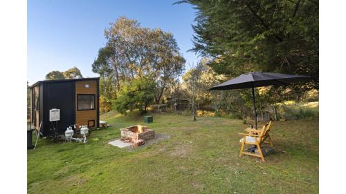 a tent in a field with an umbrella and a table at Longmore Retreat by Tiny Away in Daylesford