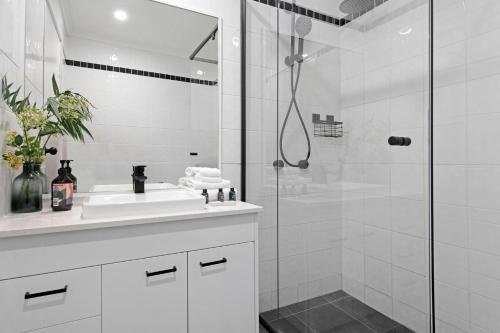 a white bathroom with a shower and a sink at Unbeatable Location - Spacious 3 bedroom townhouse in Gold Coast