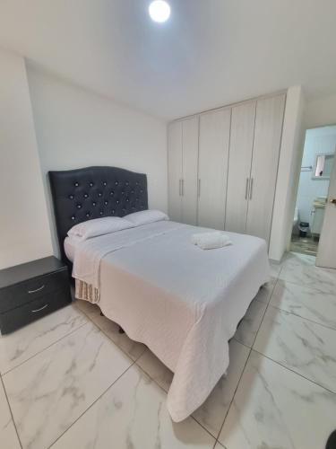 a bedroom with a bed with white sheets and a tv at Apartahotel Rubí San Gil in San Gil