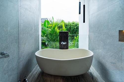 a bath tub in a bathroom with a window at Botanika Estate Private Pool Villa in Canggu