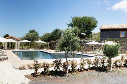 a swimming pool with trees and umbrellas at PODERE DELL'ETNA SEGRETA - Essential Nature Hotel & Glamping in Biancavilla