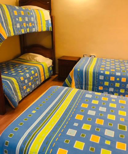 a bedroom with two beds and a bunk bed at Hostería y Centro de Convenciones Baguanchi in Cuenca