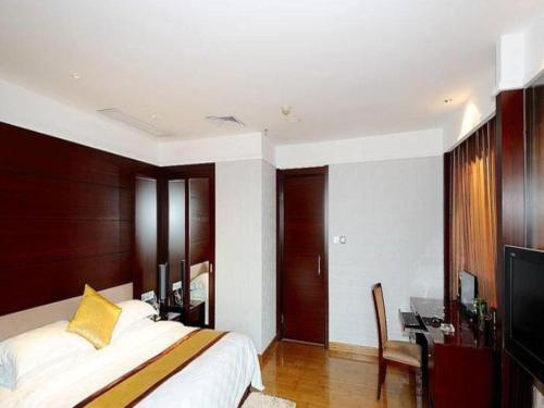 a bedroom with a bed and a desk and a television at Fuzhou Xin Zi Yang Hotel in Fuzhou