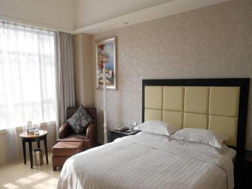 a bedroom with a large bed and a chair at Fuzhou Xin Zi Yang Hotel in Fuzhou