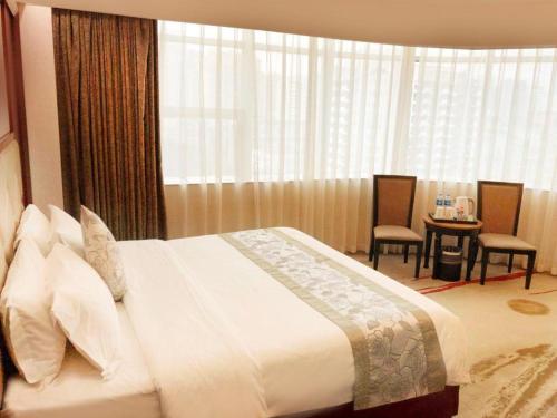 a hotel room with a bed and a table and chairs at Fuzhou Xin Zi Yang Hotel in Fuzhou