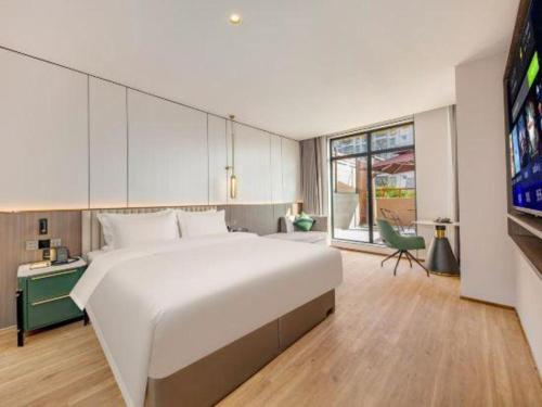 a bedroom with a large white bed and a tv at Shanshui Trends Hotel-Bantian Dong Branch in Shenzhen