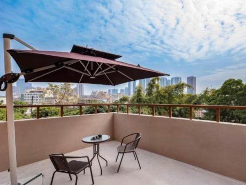 a patio with a table and chairs and an umbrella at Shanshui Trends Hotel-Bantian Dong Branch in Shenzhen