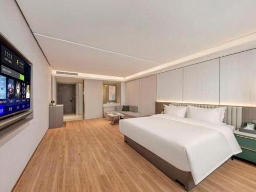 a bedroom with a white bed and a flat screen tv at Shanshui Trends Hotel-Bantian Dong Branch in Shenzhen