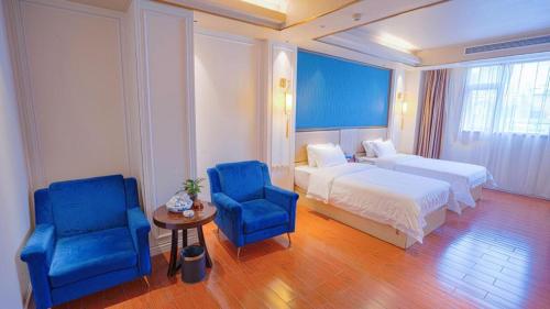 a hotel room with a bed and two blue chairs at Quanzhou Binhai Hotel in Quanzhou