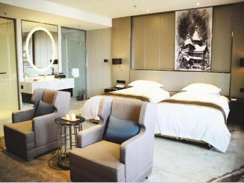 a bedroom with a bed and two chairs and a sink at Harbin Splendent Hotel in Harbin