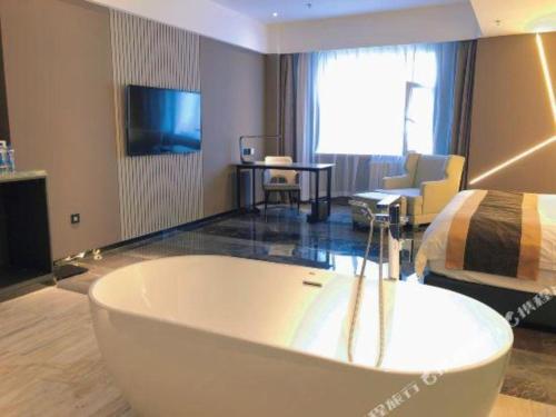 a large bathroom with a tub in front of a bedroom at Harbin Splendent Hotel in Harbin