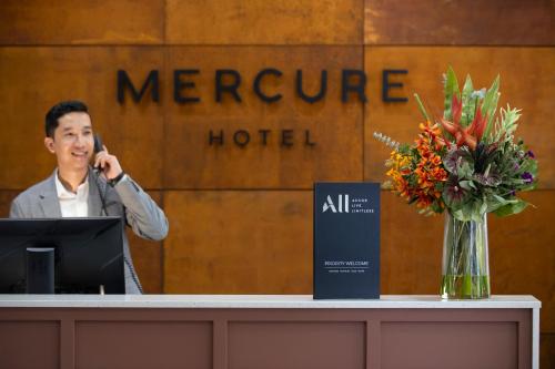 a man talking on a phone in front of a hotel at Mercure Newcastle in Newcastle