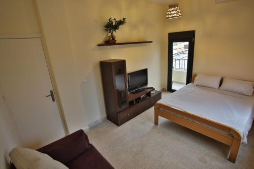 a bedroom with a bed and a tv and a couch at 3BR in Batroun Bahsa Old Souks in Batroûn