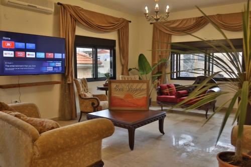 a living room with couches and a tv and a table at 3BR in Batroun Bahsa Old Souks in Batroûn