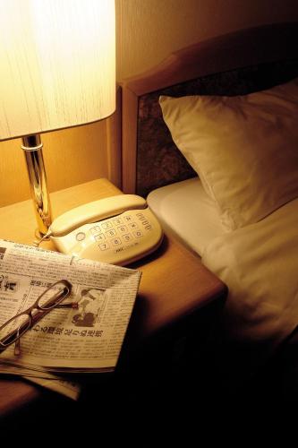 a hotel room with a bed and a newspaper and a lamp at Hirosaki Plaza Hotel in Hirosaki