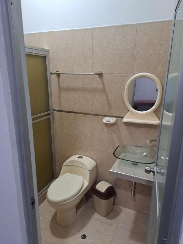 a small bathroom with a toilet and a mirror at Habitación Triple in Iquitos