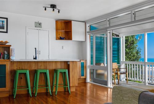 a kitchen with green stools in front of a counter at Te Hu - Ahipara Beachfront Bach in Ahipara