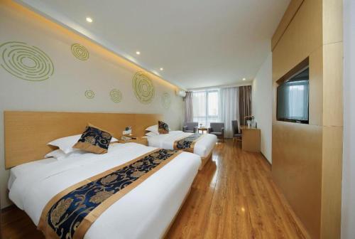 a hotel room with two beds and a television at Green Tree Inn Fengxian New City Metro Station Jiukeshu Art Center in Shanghai