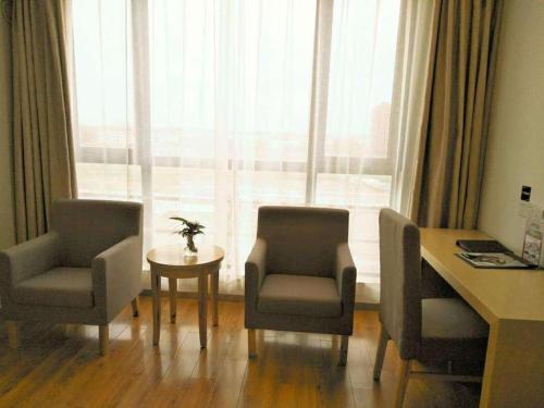 a room with two chairs and a desk and a window at Green Tree Inn Fengxian New City Metro Station Jiukeshu Art Center in Shanghai