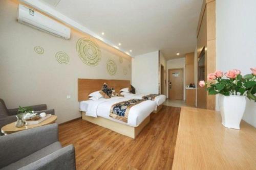 a hotel room with a bed and a vase of flowers at Green Tree Inn Fengxian New City Metro Station Jiukeshu Art Center in Shanghai