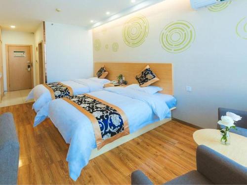 a large bedroom with two beds and a table at Green Tree Inn Fengxian New City Metro Station Jiukeshu Art Center in Shanghai