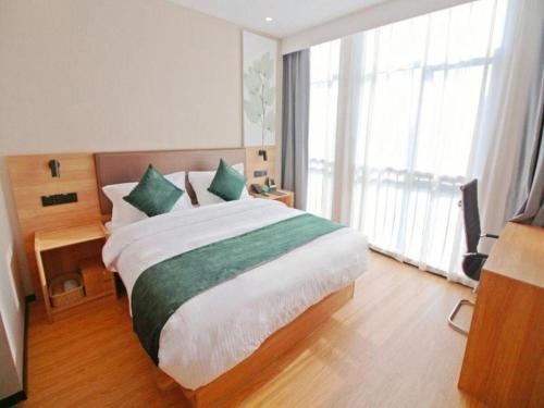 a bedroom with a large bed and a large window at GreenTree Inn Express Zhangjiagang Hexing Town Shazhou Professional Institue of Technology in Qiwei