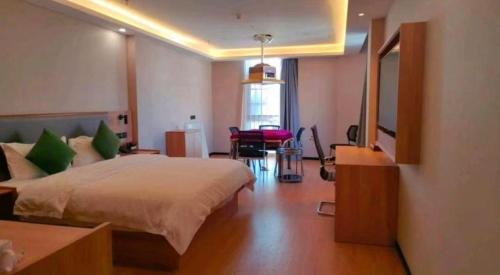 a bedroom with a large bed and a table and a desk at GreenTree Inn Express Zhangjiagang Hexing Town Shazhou Professional Institue of Technology in Qiwei