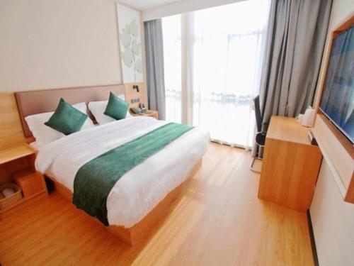 a bedroom with a large bed and a large window at GreenTree Inn Express Zhangjiagang Hexing Town Shazhou Professional Institue of Technology in Qiwei