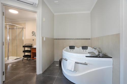 a white bathroom with a tub and a shower at City Corporate Motor Inn in Palmerston North