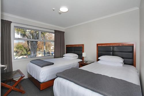 a hotel room with two beds and a window at City Corporate Motor Inn in Palmerston North