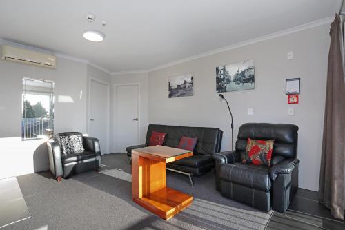 a living room with leather furniture and a table at City Corporate Motor Inn in Palmerston North