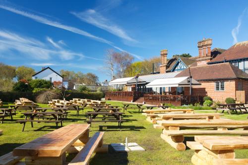 a row of wooden tables and benches in a field at The Mayflower in Lymington