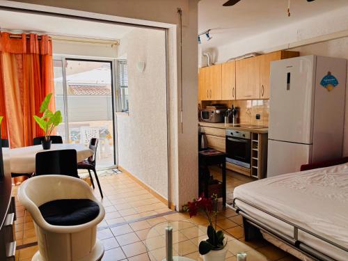 Il comprend une petite cuisine avec une table et un réfrigérateur blanc. dans l'établissement Appt RDC tout confort Clim Parking Terrasse, à Argelès-sur-Mer