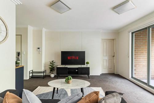 Una sala de estar con un televisor y una mesa. en Free Parking on Bunn, 5 mins to The Star & Darling, en Sídney